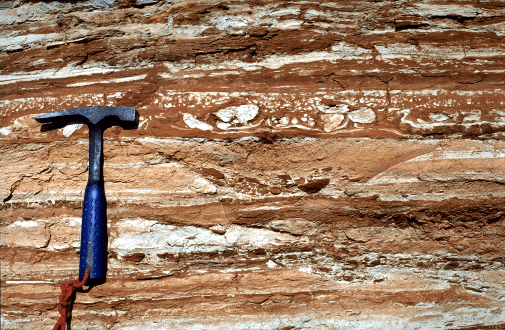 layered outcrop with hammer